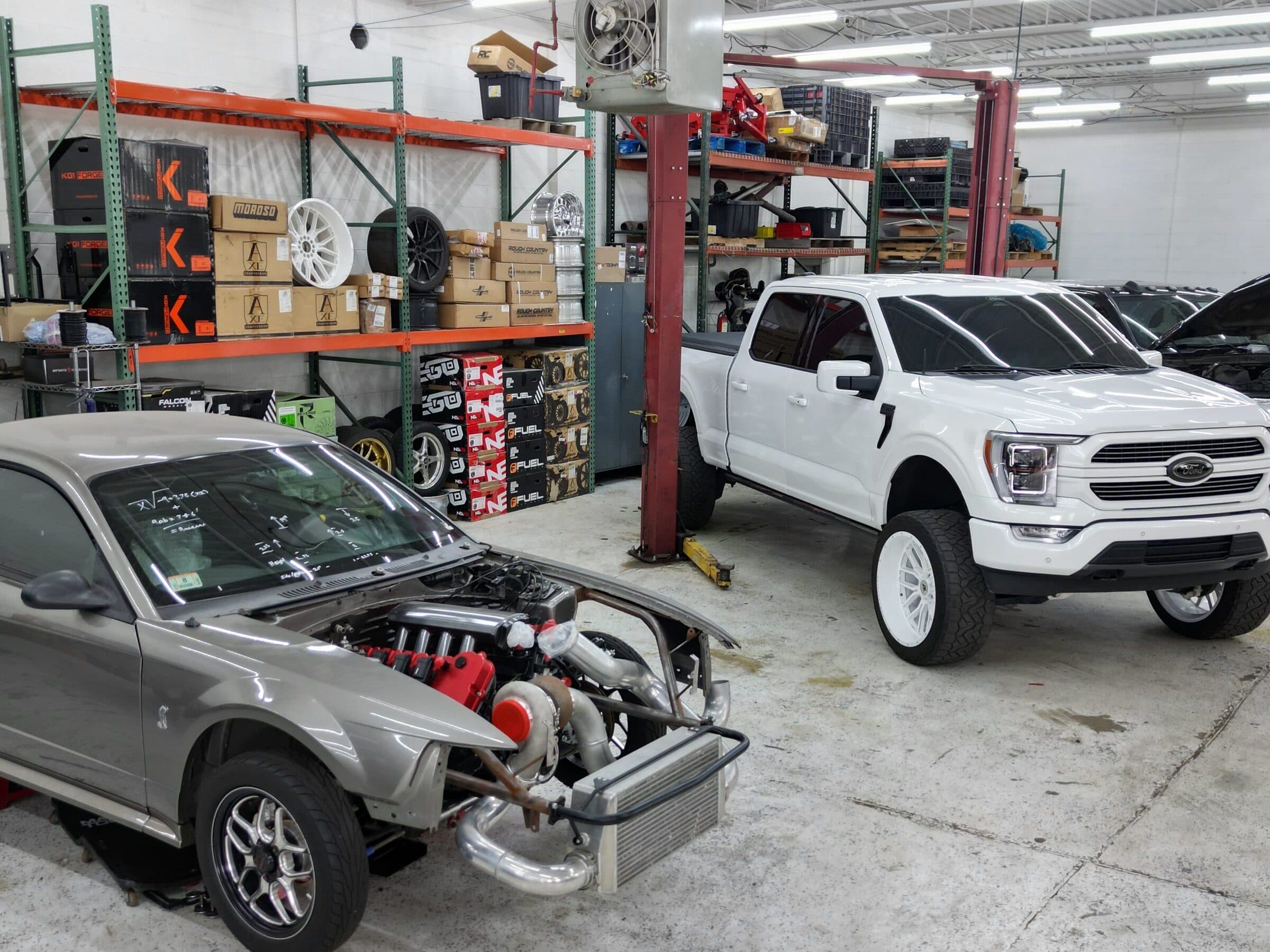 Inside the Street Justice Performance shop: a turbocharged project car and a lifted Ford F-150, with parts shelving along the wall